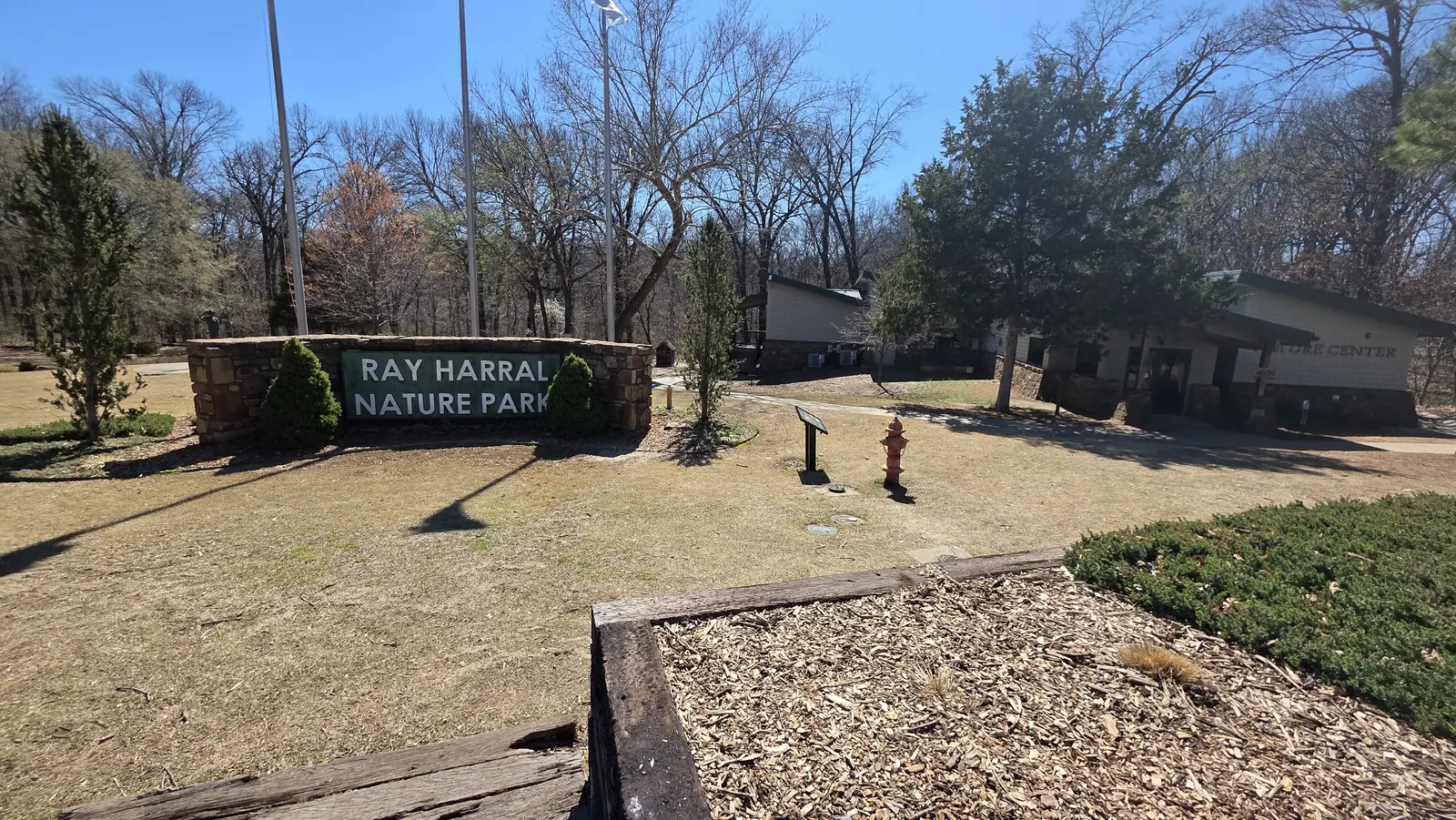 Tree-lined trail and park entrance area at Ray Harral Nature Park in Broken Arrow
