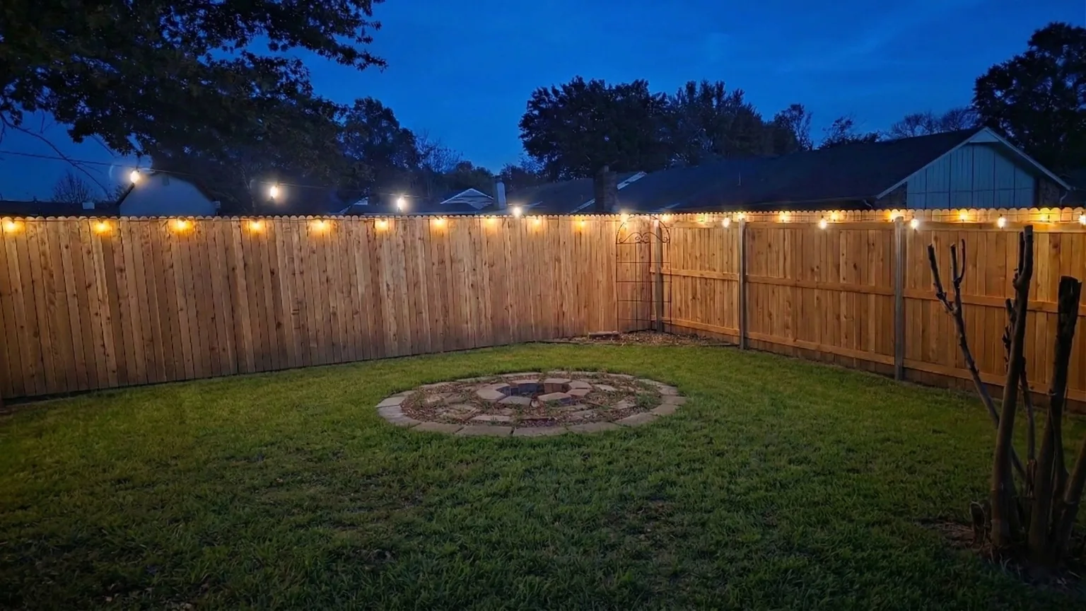 Backyard at The Space Place at dusk with string lights and a circular fire pit area