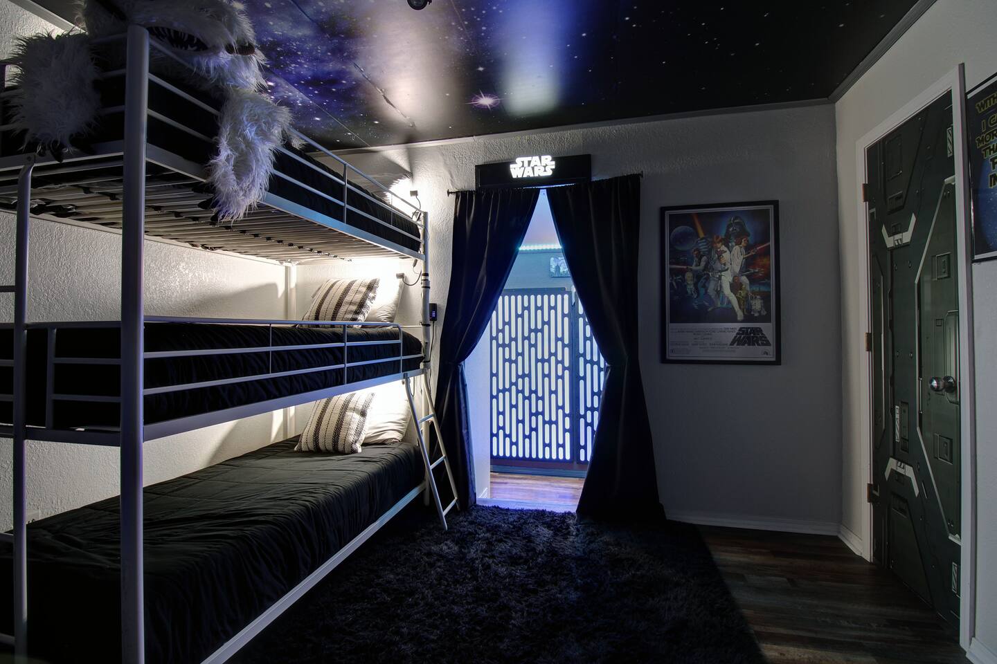 Space-themed bedroom with a triple bunk bed, themed lighting and wall art