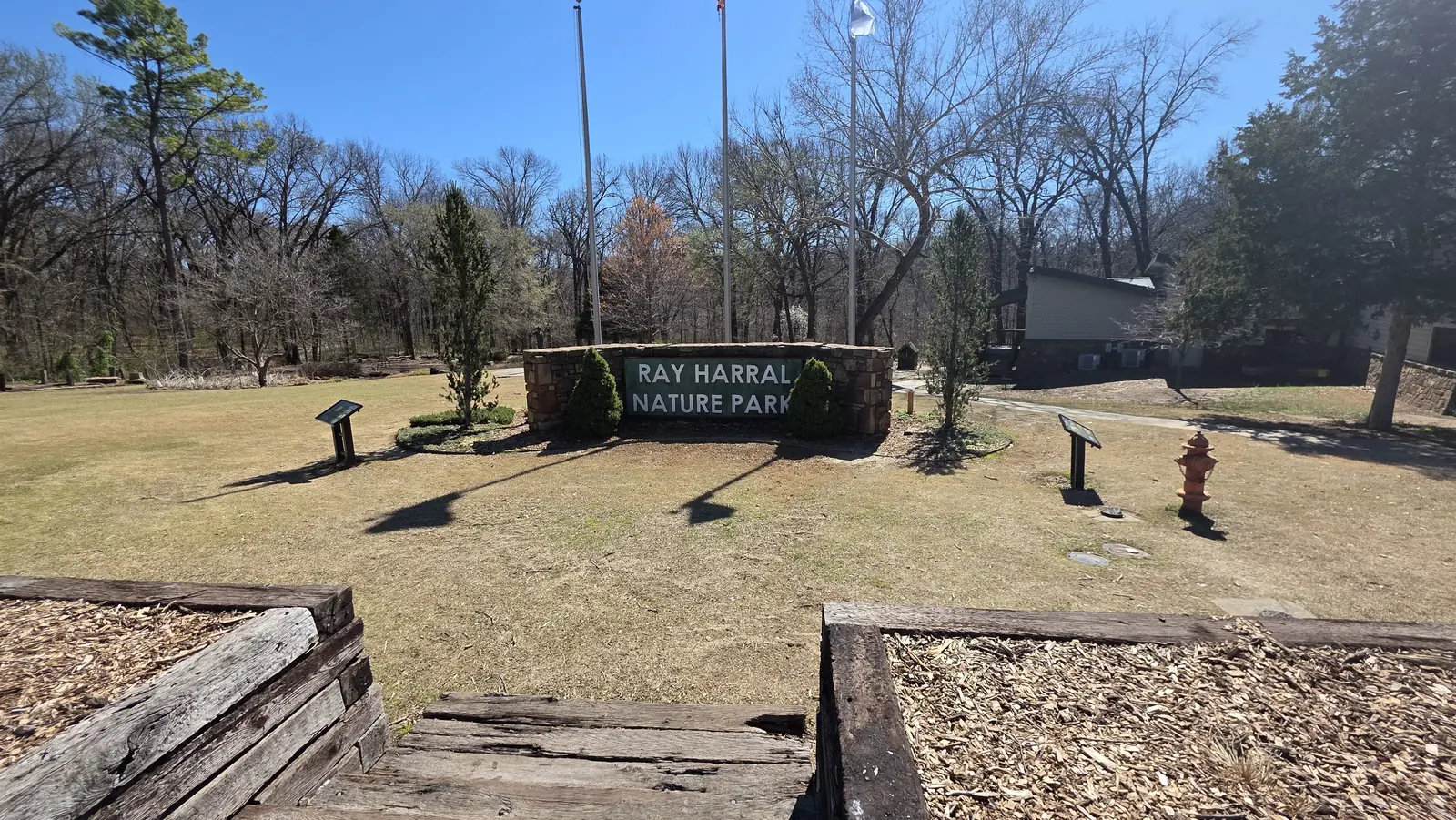 Entrance sign and tree-lined approach at Ray Harral Nature Park in Broken Arrow